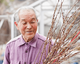 笑顔で花に接する故・阿部一郎氏